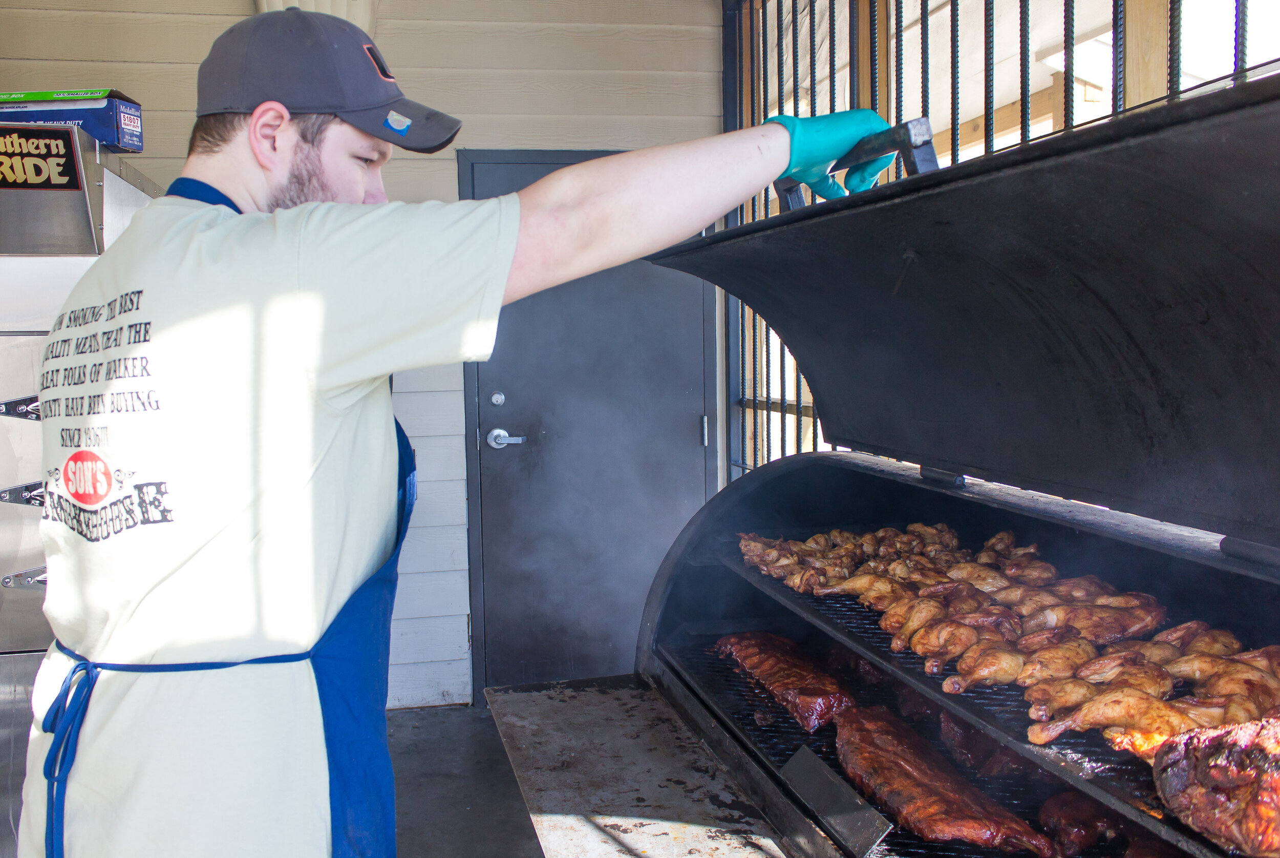 Austin Millwood behind the smoker, tending the ribs and chicken. 